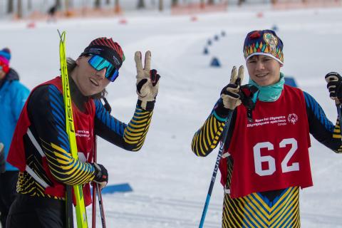 Cross country skiing athletes Francis and Sebastian smiling and both showing peace signs