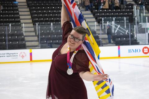 SOBC Athlete Kari Trott holds flag while figure skating