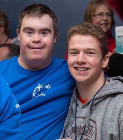 Logan smiles at the camera with a Special Olympics athlete