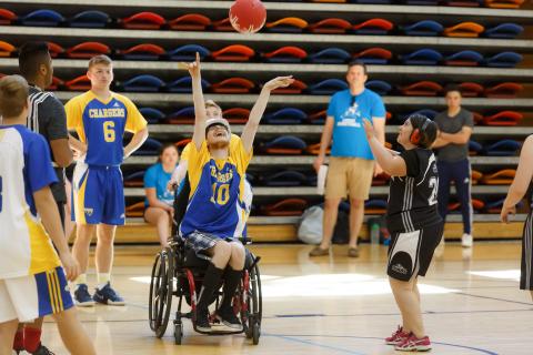 An athlete from a wheelchair tosses a basketball in the air